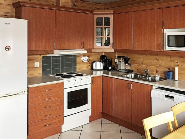 A kitchen with wooden cabinets, a stove, a microwave, and a Siemens dishwasher. - 6 Person Holiday Home in Seim (Alver)