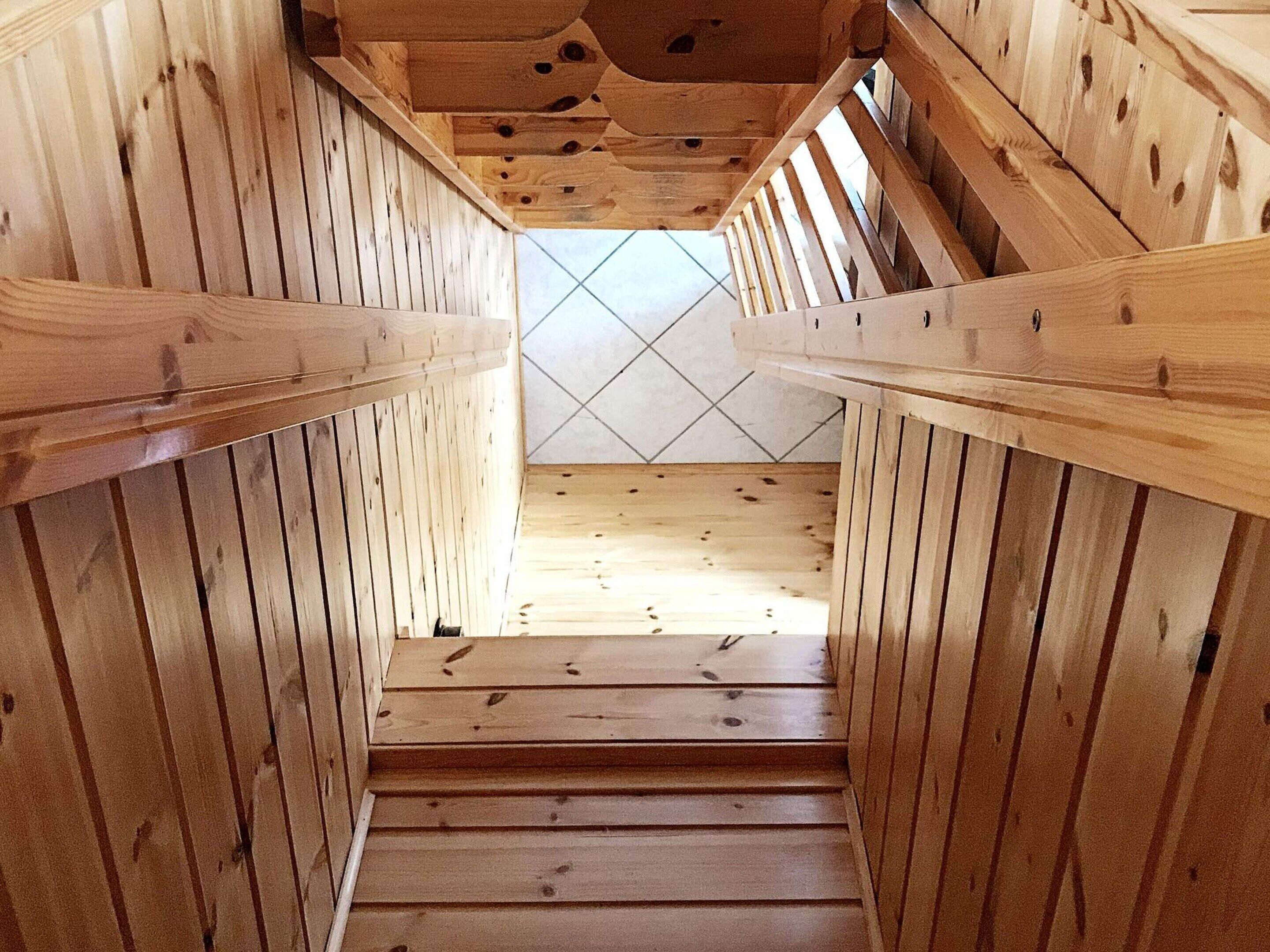 A wooden staircase with a tiled floor and wooden railings.