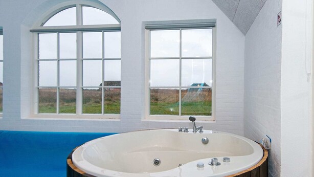 A modern bathroom with a freestanding bathtub, large windows, and a view of the outdoors. - 16 Person Holiday Home in Ulfborg (Ulfborg)