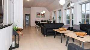 A spacious living area with a dining table, sofas, and a kitchen area. - 16 Person Holiday Home in Ulfborg (Ulfborg)