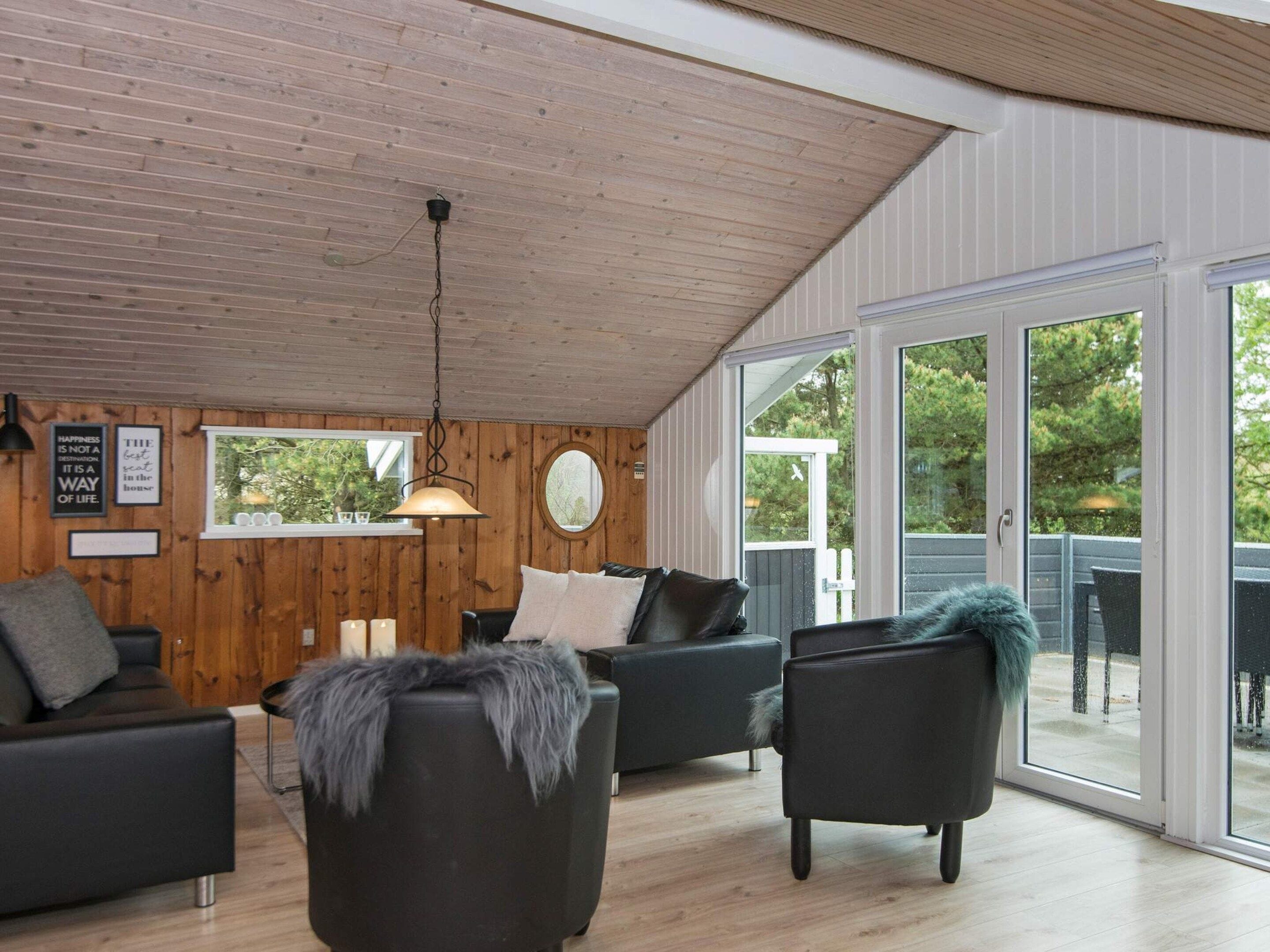 A modern living room with wooden panel walls, a ceiling fan, and a large sliding glass door leading to an outdoor area.