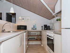 A compact kitchen with a microwave, coffee maker, and a built-in oven.