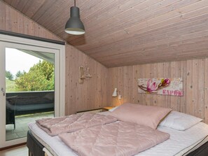A bedroom with a bed, a wooden ceiling, a window, and a wall-mounted light fixture. - 6 Person Holiday Home in Romo (Rømø)