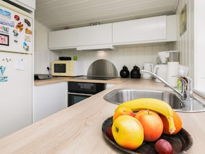 A kitchen with white cabinets, a microwave, a stove, and a sink. - 4 Person Holiday Home in Assens (Assens)