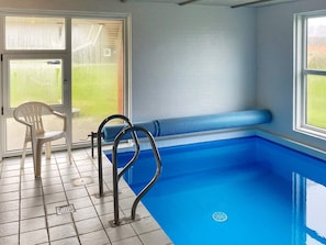A swimming pool with a bench and a chair, a tiled floor, and a window with a view of greenery. - 4 Star Holiday Home in Nordborg (Nordborg)