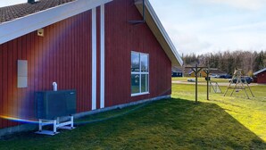 A red building with a sloped roof, a window, and a small outdoor area with a swing set. - 4 Star Holiday Home in Nordborg (Nordborg)
