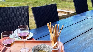 A blue outdoor table with wicker chairs, a glass of wine, and a bowl of snacks. - 4 Star Holiday Home in Nordborg (Nordborg)