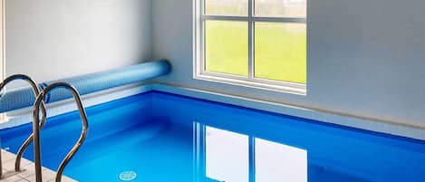 Una piscina con una ventana, una escalera y suelo de baldosas.