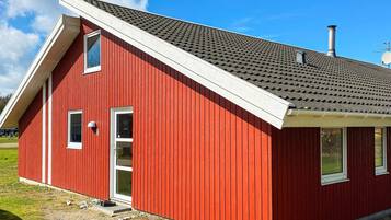 A red building with a sloped roof, a chimney, and a small porch area.