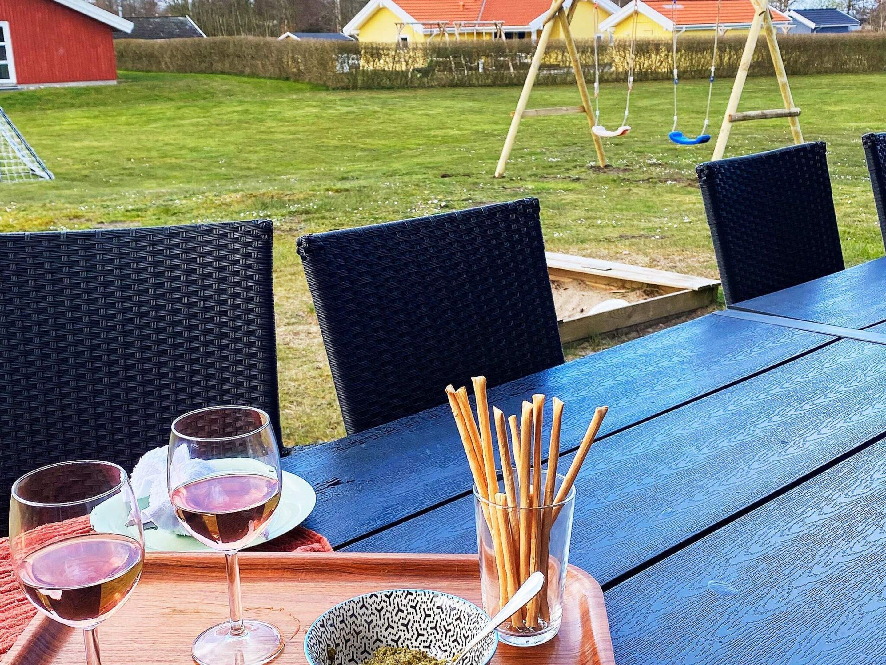 Una mesa azul al aire libre con sillas de mimbre, una copa de vino y un bol de aperitivos.