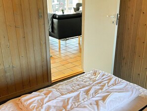 A bedroom with a bed, wooden wardrobe, and a view of the outside. - 4 Star Holiday Home in Nordborg (Nordborg)