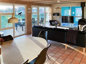 A modern kitchen with a dining area, large windows, and a view of the outdoors.