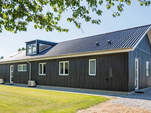 A modern building with a sloped roof, multiple windows, and a small attached structure.