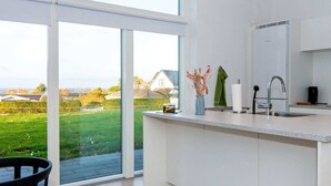 Une cuisine moderne dotée d’une grande fenêtre, d’un évier encastré et offrant une vue sur un paysage verdoyant.
