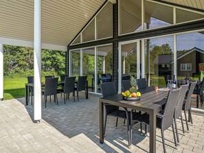 An outdoor patio with a table set for dining, surrounded by chairs, and a fruit bowl on the table. - Holiday Home in Grenaa (Grenaa)