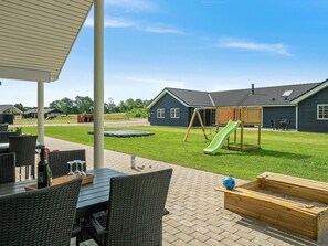 A patio area with outdoor furniture, a trampoline, and a play structure. - Holiday Home in Grenaa (Grenaa)