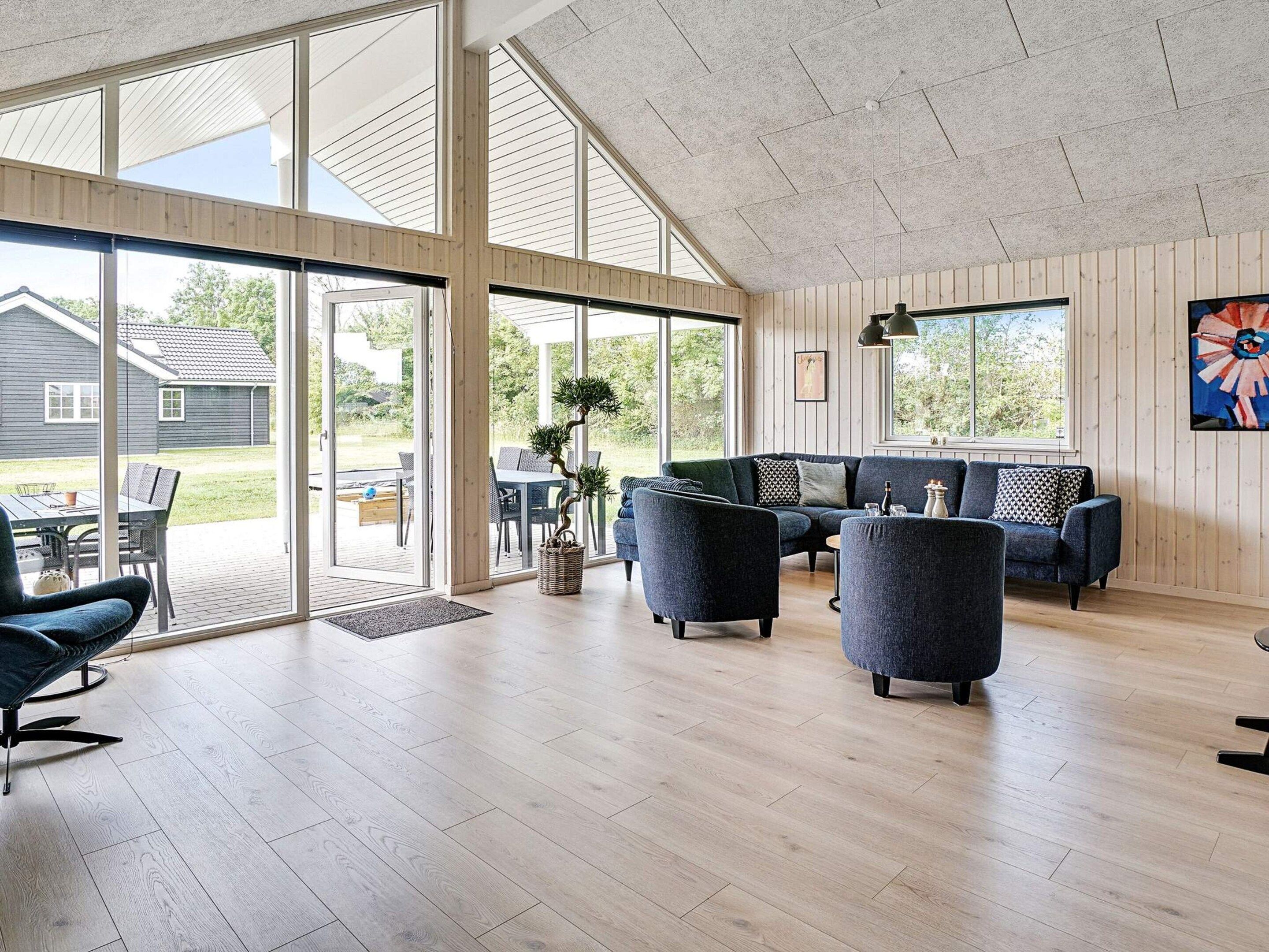 A spacious living area with a large sliding glass door leading to an outdoor patio, a dark blue sofa set, and a potted plant.