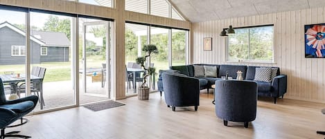 A spacious living area with a large sliding glass door leading to an outdoor patio, a dark blue sofa set, and a potted plant.