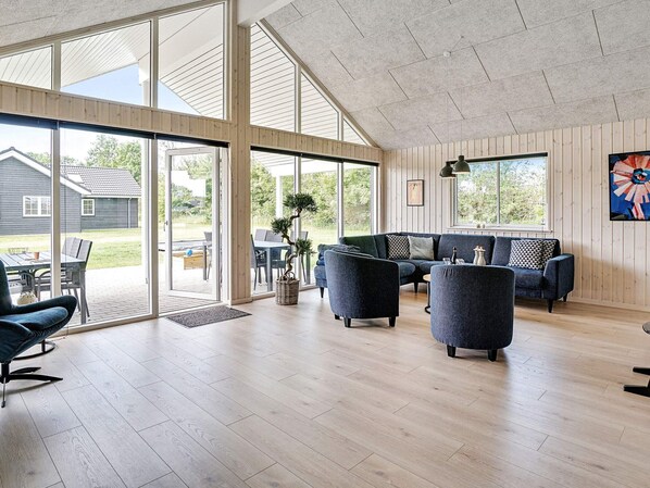 A spacious living area with a large sliding glass door leading to an outdoor patio, a dark blue sofa set, and a potted plant.