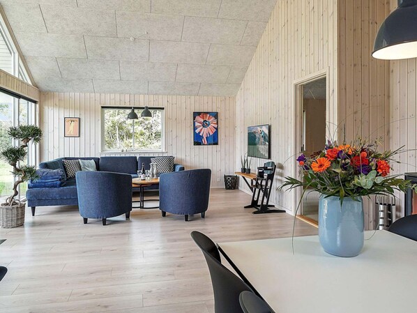Un salon moderne comprenant un canapé, des fauteuils, une table à manger et une grande fenêtre.