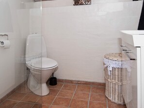 A bathroom with a toilet, a trash bin, and a wicker basket. - 6 Person Holiday Home in Ebeltoft (Ebeltoft)