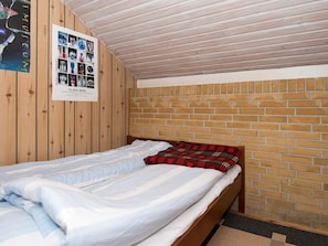 A small, cozy room with a single bed, wooden walls, and a brick accent wall. - 6 Person Holiday Home in Ebeltoft (Ebeltoft)