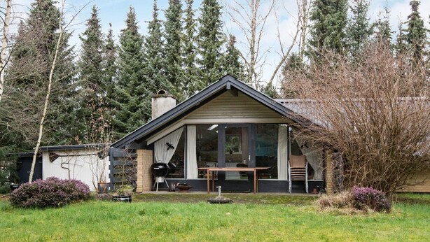 A modern house with a large glass door, a patio with a table and chairs, and a grassy yard. - 6 Person Holiday Home in Ebeltoft (Ebeltoft)