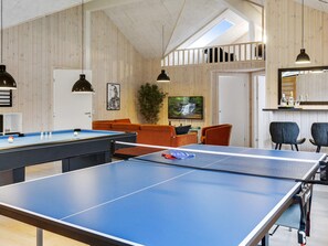 A room with ping pong tables, a sofa, and a TV. - Holiday Home in Idestrup (Idestrup)