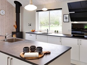 Una cocina moderna con una isla central, estufa integrada y ventana con vistas al exterior.