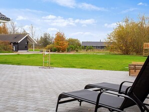 A paved patio area with a seating arrangement and a swing set. - Holiday Home in Idestrup (Idestrup)