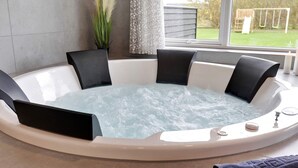 Ein Whirlpool mit vier schwarzen Stühlen, ein Fenster mit Blick auf einen Garten und eine kleine Pflanze auf dem Fensterbrett.
