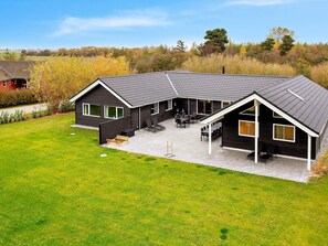 A modern two-story house with a covered patio area and a lawn. - Holiday Home in Idestrup (Idestrup)