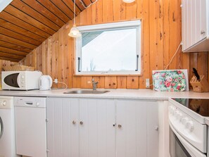 A compact kitchen with wooden walls, a window, a microwave, a kettle, a sink, and a dishwasher. - 5 Person Holiday Home in Hejls (Hejls)