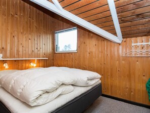 A bedroom with wooden walls, a skylight, a bed with white bedding, a small window, and a wall-mounted light fixture. - 5 Person Holiday Home in Hejls (Hejls)