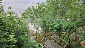 A wooden staircase leading through dense foliage towards a beach.