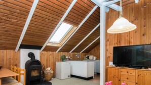 A cozy room with a fireplace, a television, wooden walls, a skylight, and a dining area. - 5 Person Holiday Home in Hejls (Hejls)