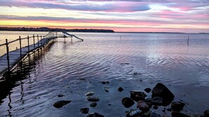 A pier extending into calm water with a sunset sky.