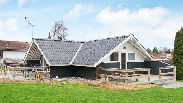 A house with a sloped roof, a deck, and a fenced yard.