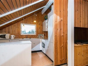 A compact kitchen with wooden walls, a window, a microwave, a kettle, and a sink. - 5 Person Holiday Home in Hejls (Hejls)
