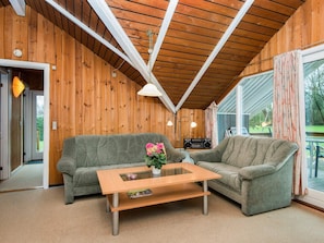 A cozy living room with wooden walls, a wooden ceiling, a glass coffee table, and two grey sofas. - 5 Person Holiday Home in Hejls (Hejls)