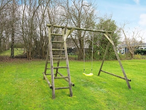 A wooden swing set in a grassy yard with trees and a house in the background. - 5 Person Holiday Home in Hejls (Hejls)