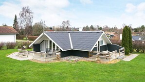 A house with a sloped roof, a deck, and a large lawn. - 5 Person Holiday Home in Hejls (Hejls)