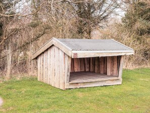 A wooden doghouse with a sloped roof and a small entrance.