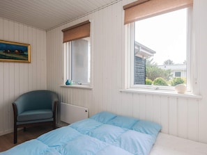 A room with a bed, a chair, a window with a view, a radiator, and a painting on the wall. - 6 Person Holiday Home in Ringkobing (Ringkobing)