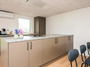 A modern kitchen with a large island, a window, and bar stools.
