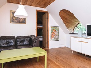 A cozy living room with a leather sofa, a green table, and a white cabinet. - 6 Person Holiday Home in Blavand (Blavand)
