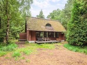 A rustic cabin with a thatched roof, surrounded by dense forest. - 6 Person Holiday Home in Blavand (Blavand)