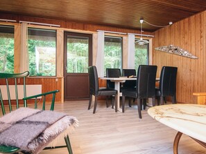 A wooden-paneled room with a dining table and chairs, large windows, and a ceiling fan. - 6 Person Holiday Home in Blavand (Blavand)