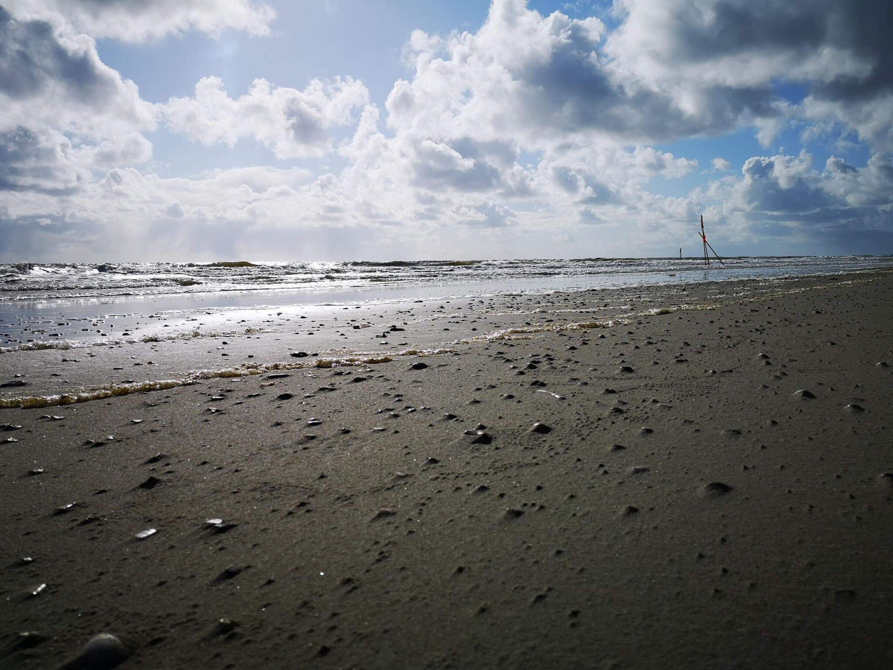 Ein Strand mit sandigem Ufer und Wellen.