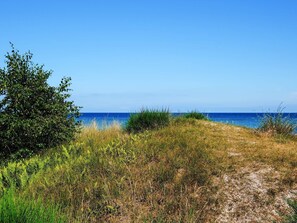 A coastal path with grass and shrubs, leading to a clear blue sea under a bright sky. - Holiday Home in VÃ¦ggerlÃ¸se (Vaeggerlose)